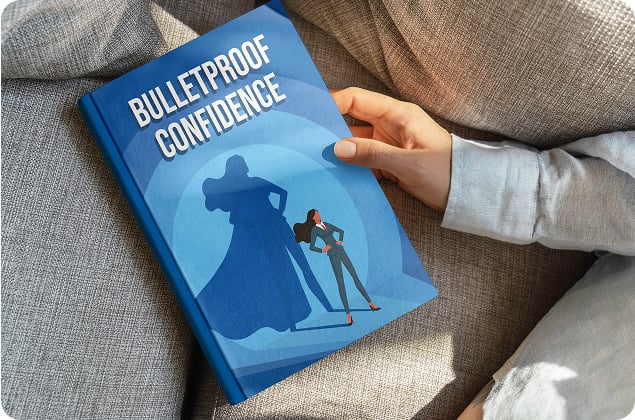 A person holding a book titled Bulletproof Confidence with an image of a woman and her heroic shadow on the cover